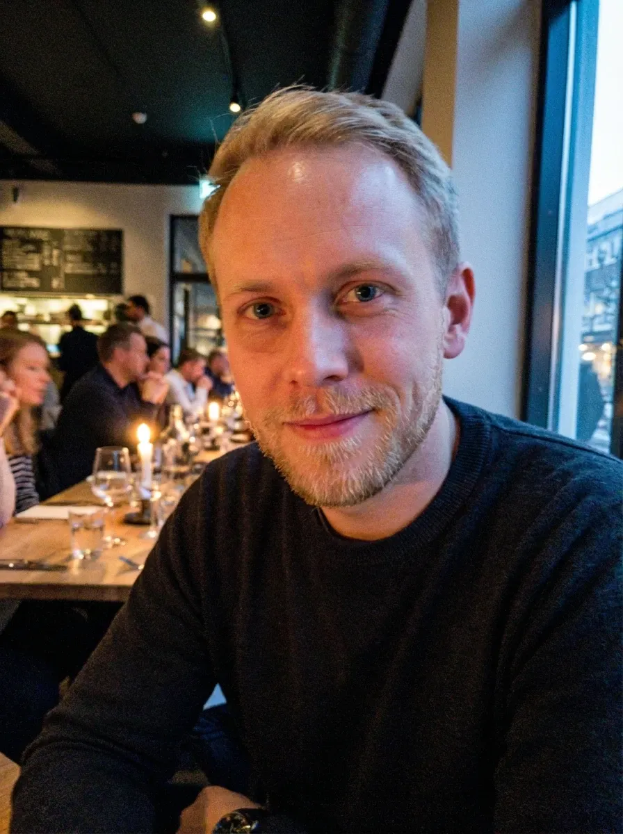 Original selfie input — man in a black sweater at a restaurant